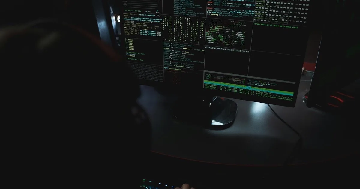 Laptop displaying code in a dark room, illustrating modern cyber threats
