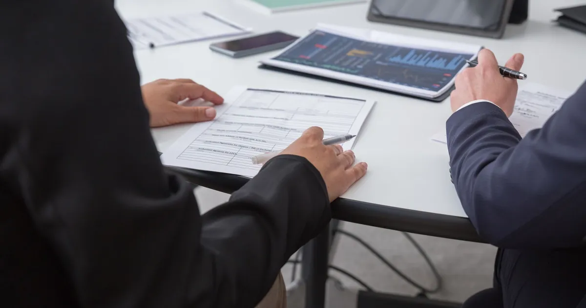 A pen test report should show the path, not only a scanner export Two people reviewing a printed penetration test findings packet