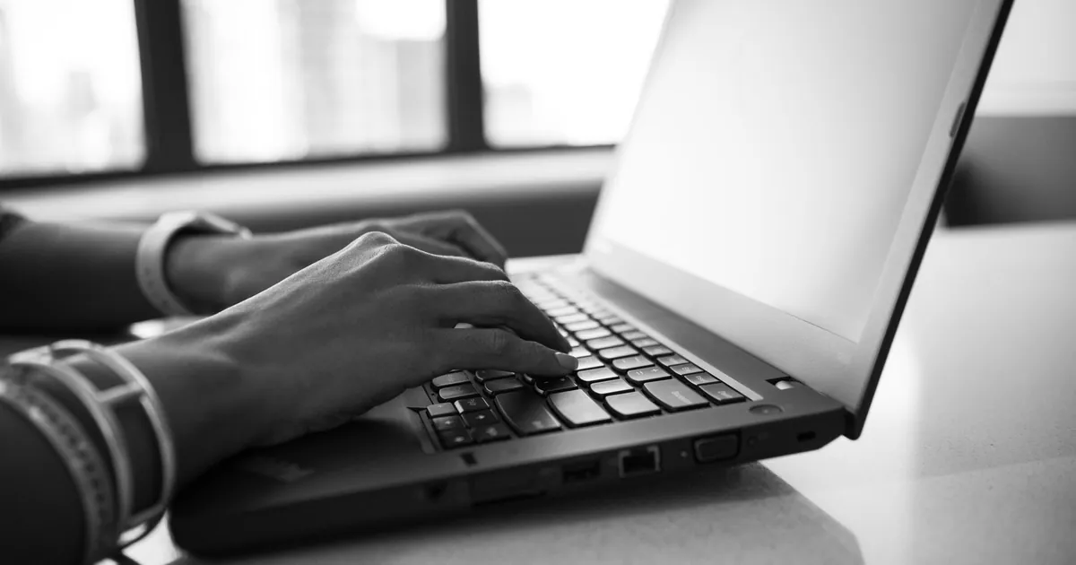 Hands on a laptop at an office desk