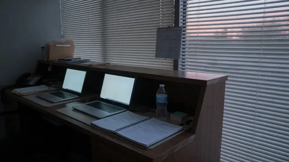 Early morning clinic reception desk with two laptops glowing and an appointment book closed