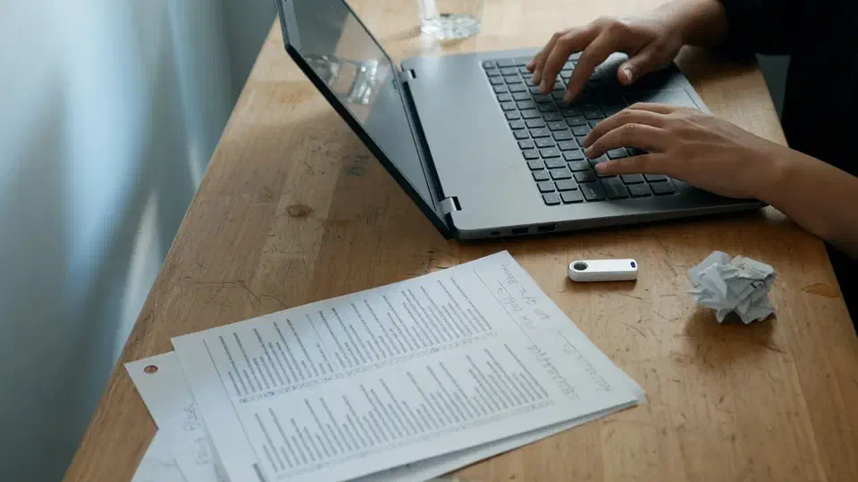 Hands at a laptop with a USB recovery drive on the desk