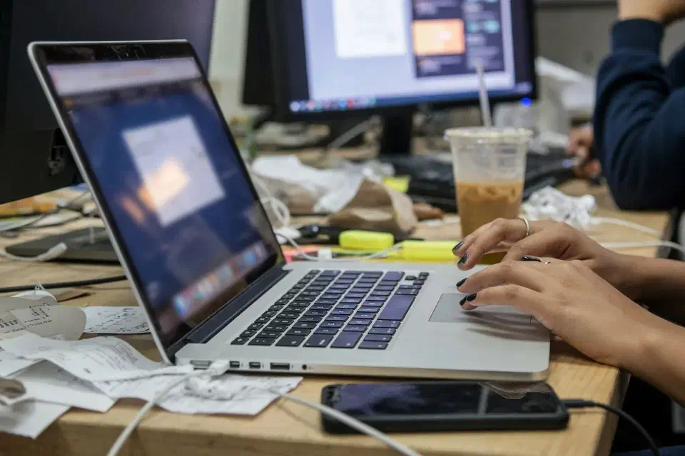 Hands at a laptop in a startup, screens out of focus