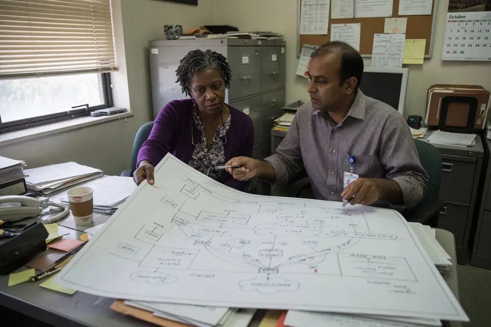 Two adults reviewing an out-of-focus network diagram