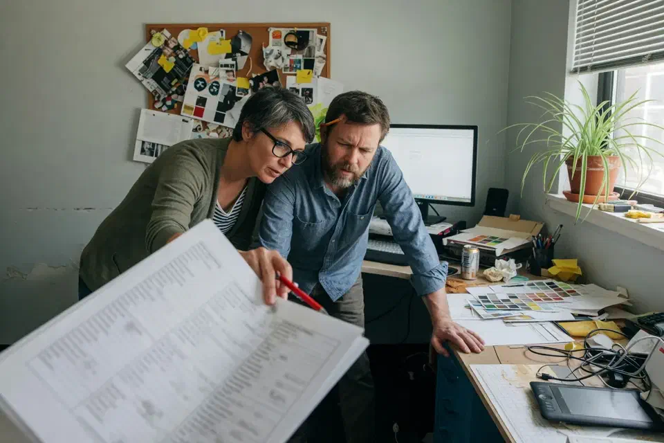 Two people reviewing an out-of-focus file list in a creative office