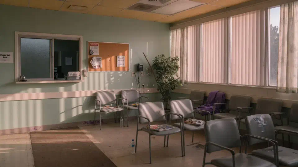 Empty suburban clinic waiting room with a frosted check-in window in late afternoon light