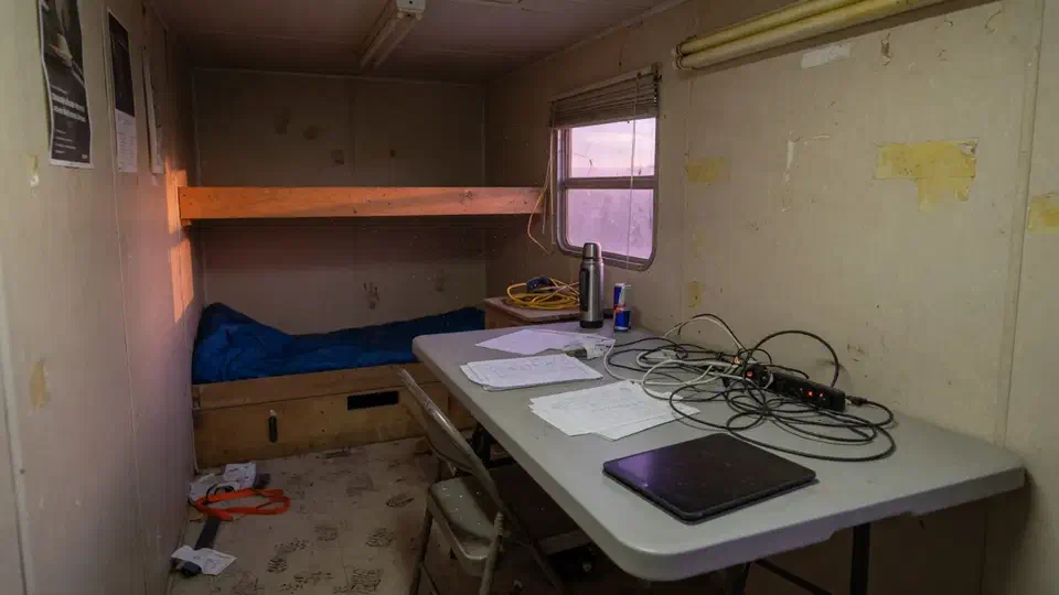 Jobsite trailer interior used as an office, tablet face down on a folding table