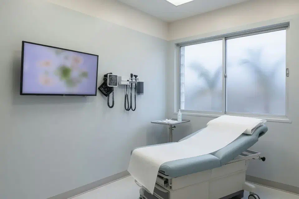 Empty modern medical exam room with a blurred clinical monitor