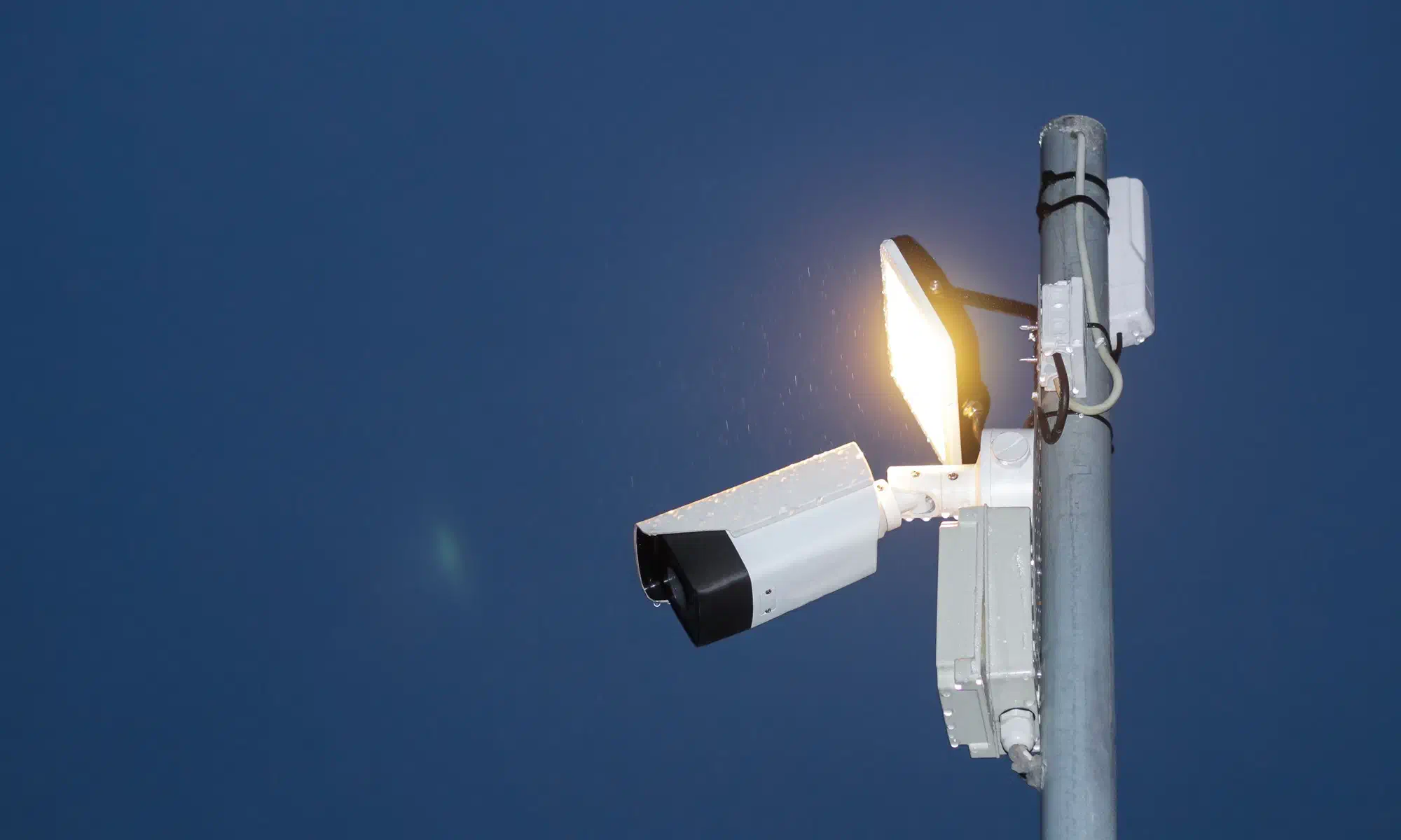 HD security camera and floodlight on a pole watching a site at dusk