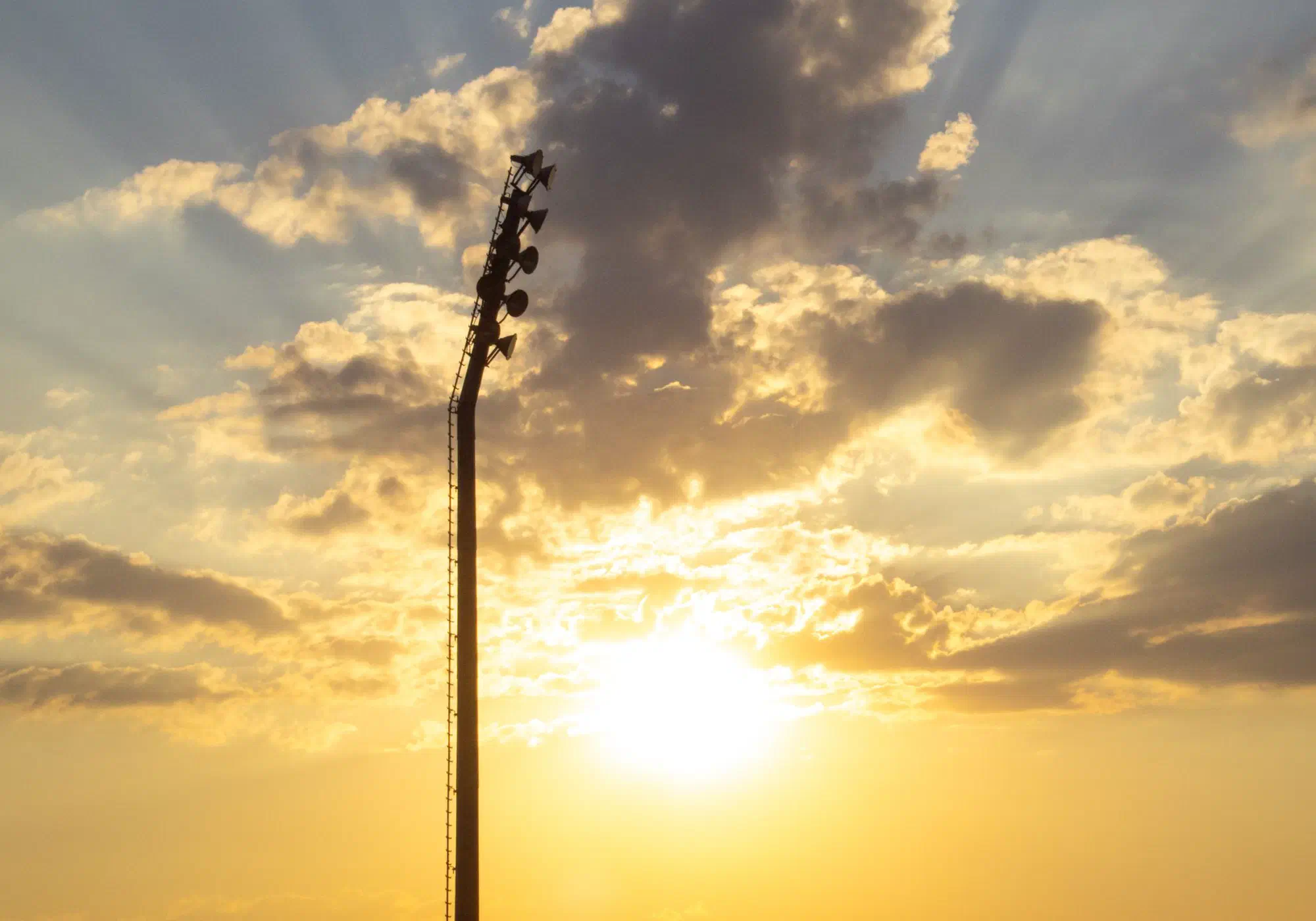Solar-powered site security tower silhouetted against a dramatic dusk sky